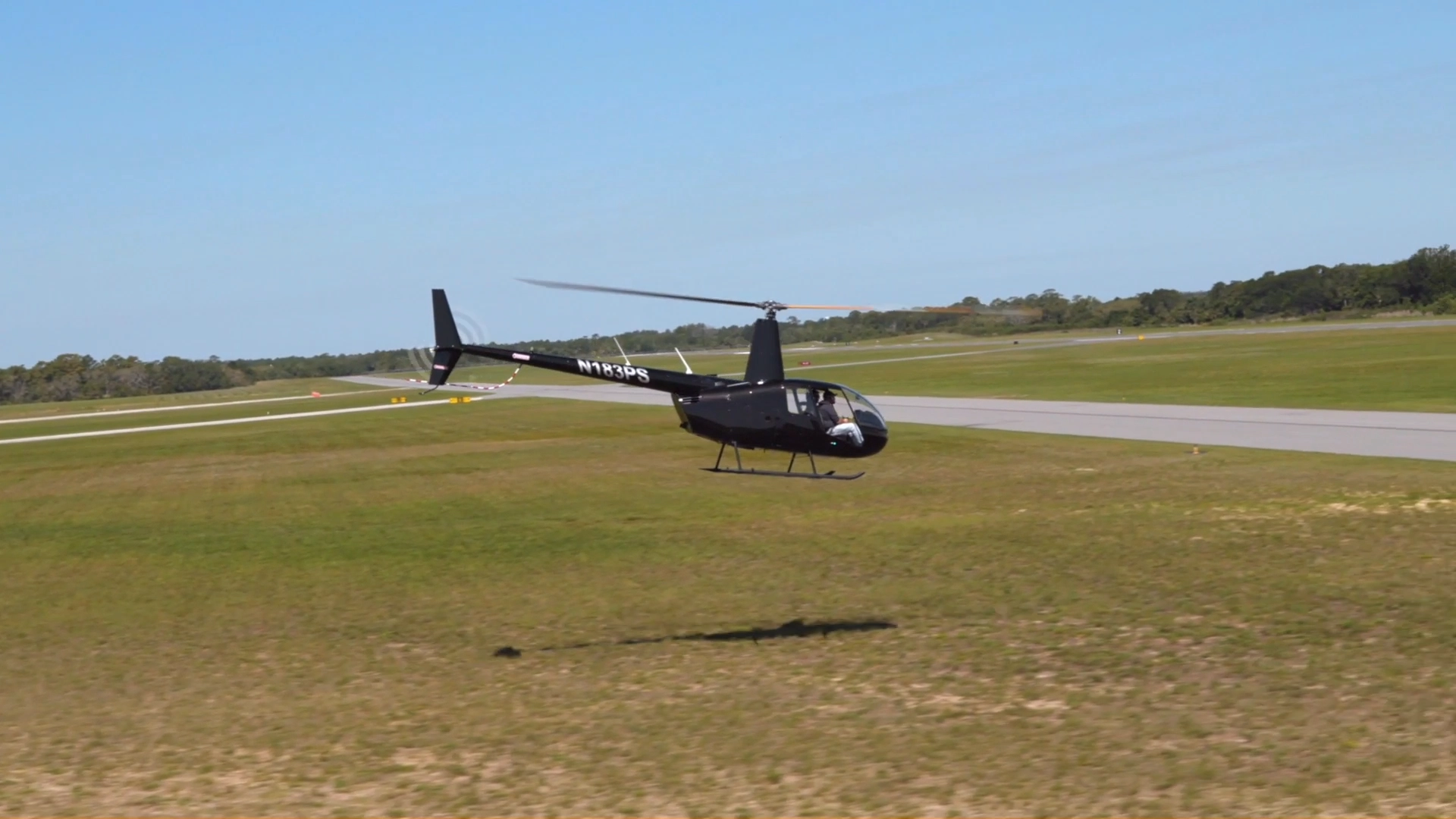 USATS training helicopter flying low over the grass at Space Coast Regional Airport